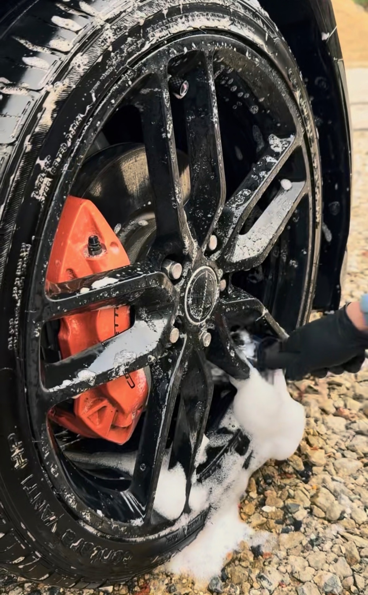 Deep wheel decontamination with foam on black alloy + red brake caliper